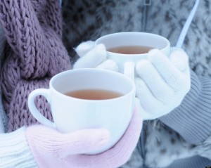Close-up of two young women holding hot tea on winter day